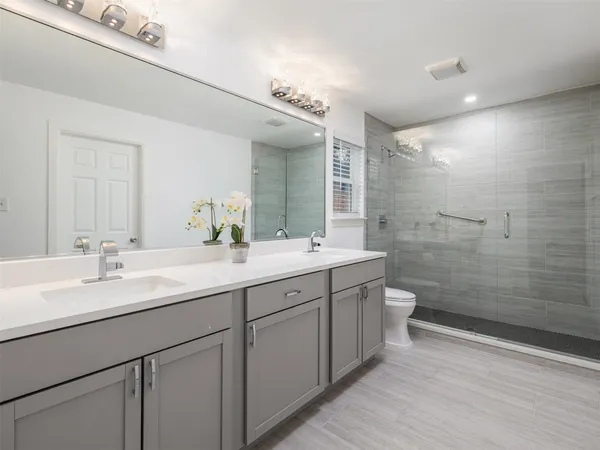 a bathroom with a double vanity sink mirror and shower