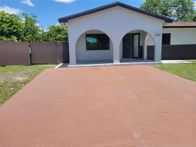 a front view of house with yard and trees in the background