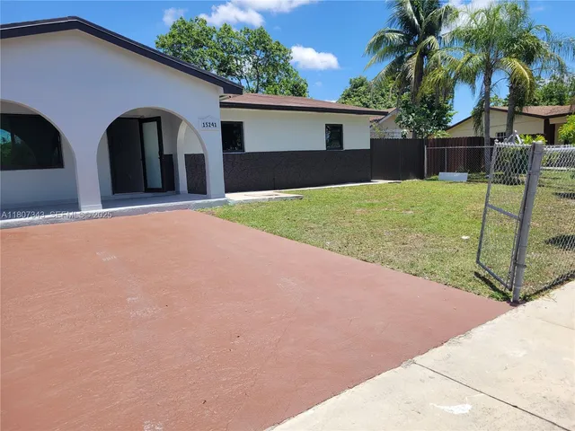 a view of a house with backyard and a tree