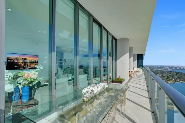 a living room with furniture a flat screen tv and a floor to ceiling window