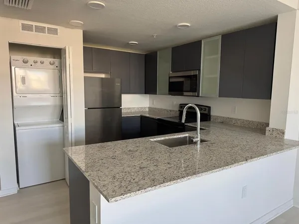 a kitchen with kitchen island granite countertop a sink and a refrigerator