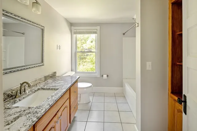 a spacious bathroom with a granite countertop sink a mirror and a bathtub