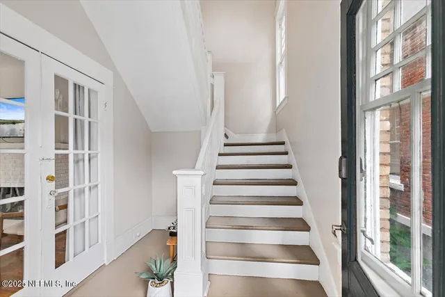 a view of staircase with lots of frames on wall and a large window