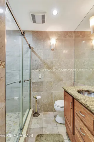 a bathroom with a granite countertop sink a toilet and shower