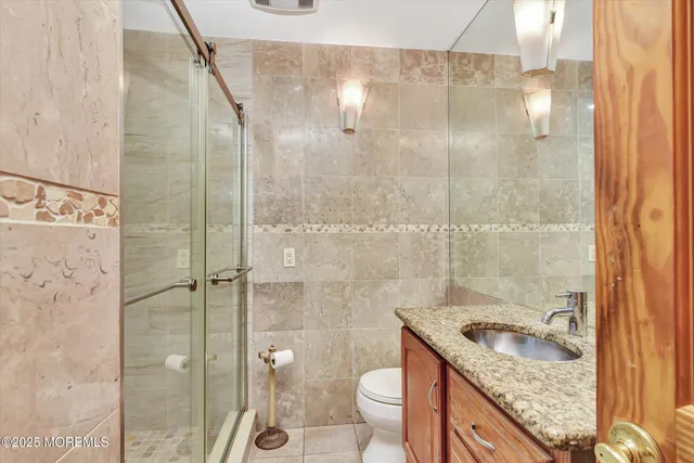 a bathroom with a granite countertop sink a toilet and shower