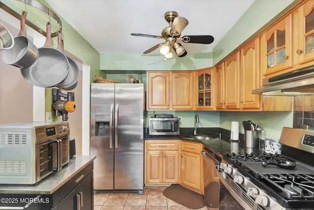 a kitchen with stainless steel appliances granite countertop a sink a stove and a refrigerator