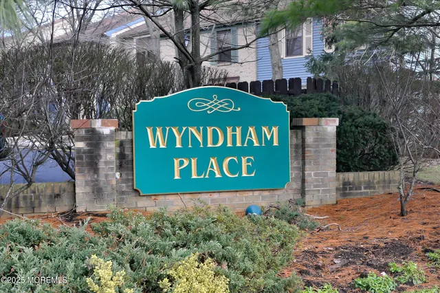 a sign that is sitting on a brick wall with large trees