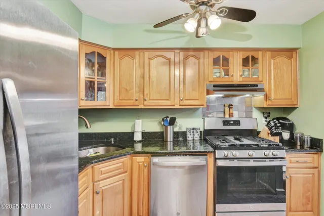 a kitchen with stainless steel appliances granite countertop a stove a sink and a refrigerator