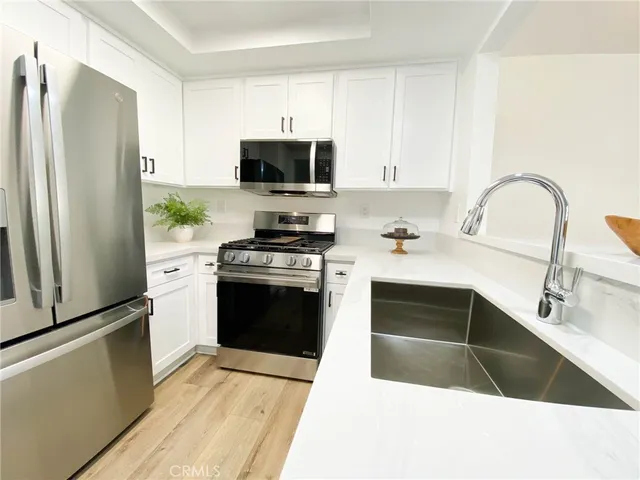 a kitchen with stainless steel appliances kitchen island granite countertop a refrigerator stove and sink