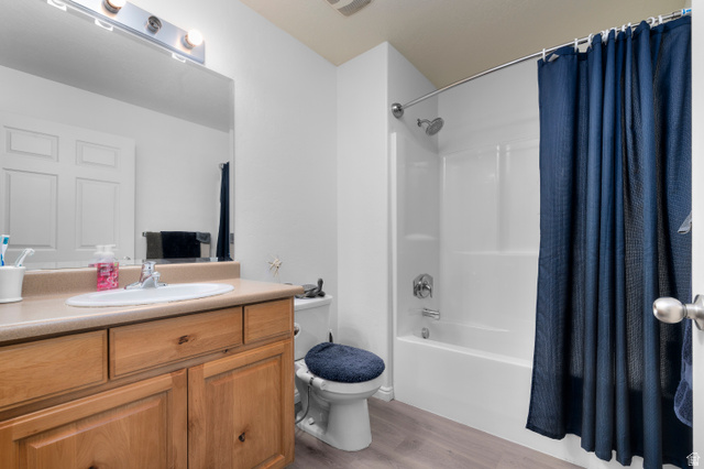 25 West Ridge Road, Unit 25 Saratoga Springs, UT 84045 - Photo 9 of 22 Bathroom featuring a light wood-finish vanity with an integrated sink, a large wall-mounted mirror, a three-light vanity bar, a white tub with shower, and wood-finish flooring