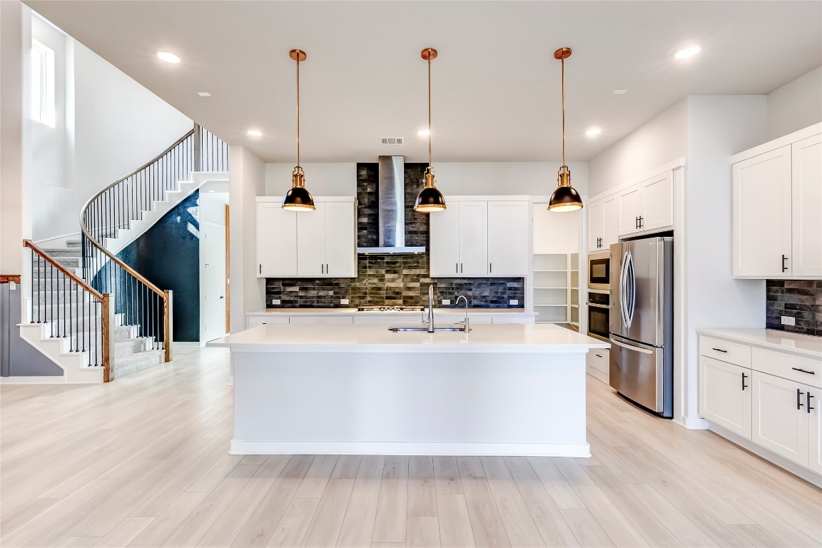 129 Cotton Tree Terrace Dripping Springs, TX 78620 - Photo 12 of 40 a large kitchen with stainless steel appliances kitchen island a large counter top and wooden floors