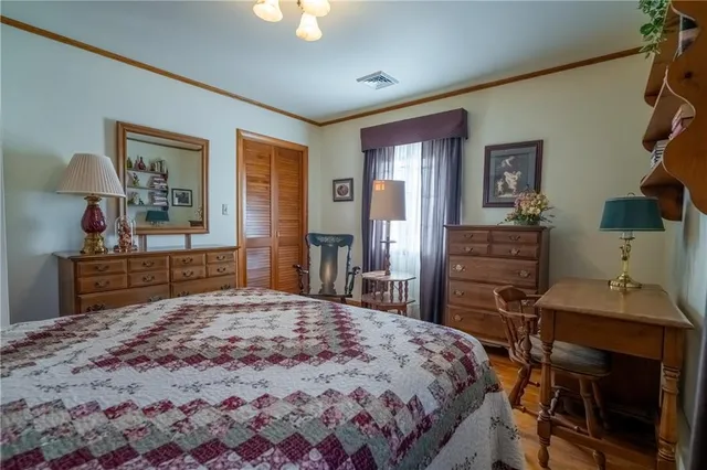a bedroom with a bed and dresser with wooden floor