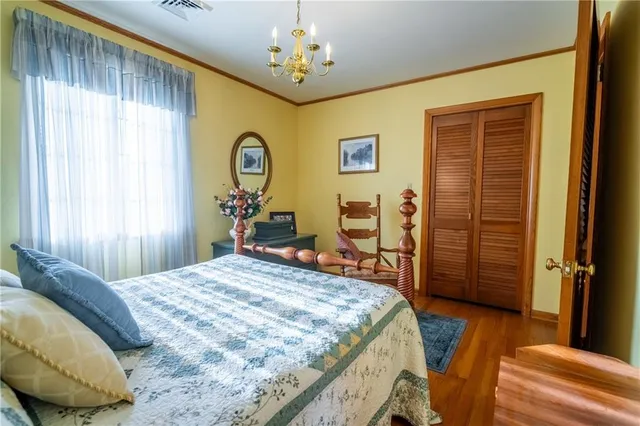 a bedroom with a bed a mirror on dresser and a wooden floor