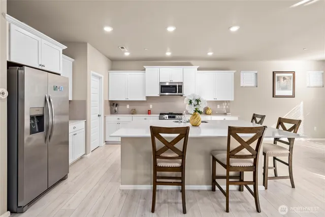 a kitchen with stainless steel appliances wooden floor and chairs