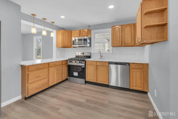 a large kitchen with stainless steel appliances granite countertop a stove a sink dishwasher and a microwave oven with cabinets