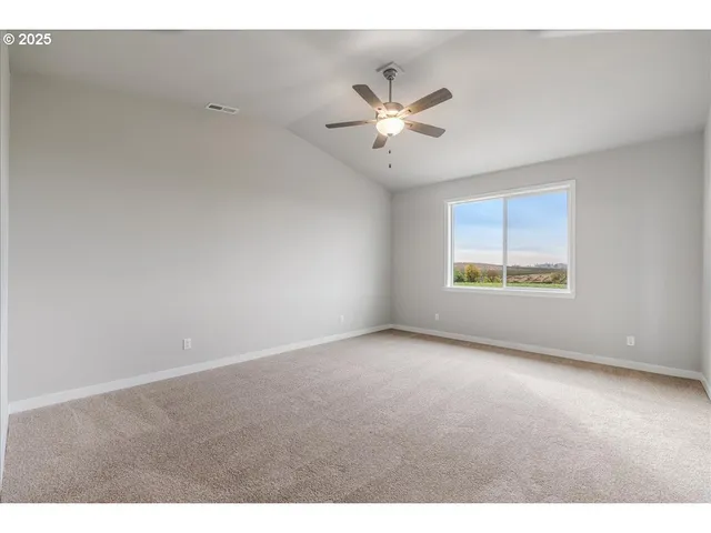 a view of an empty room with chandelier fan