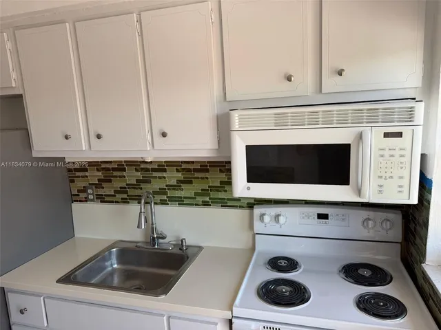 a kitchen with a stove and white cabinets