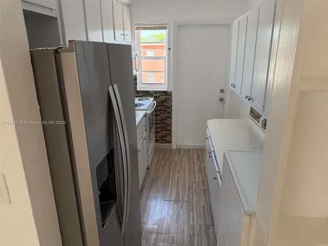 a walk in closet with wooden floor washer and dryer