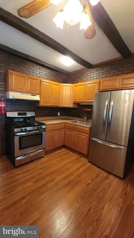 a large kitchen with wooden floors and stainless steel appliances