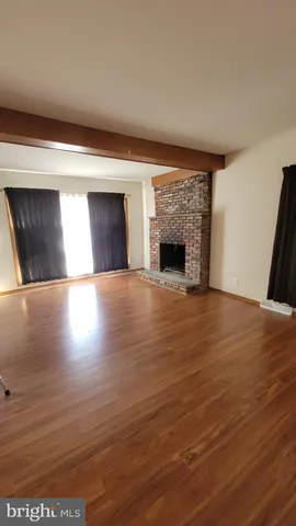 a view of an empty room with wooden floor and a fireplace