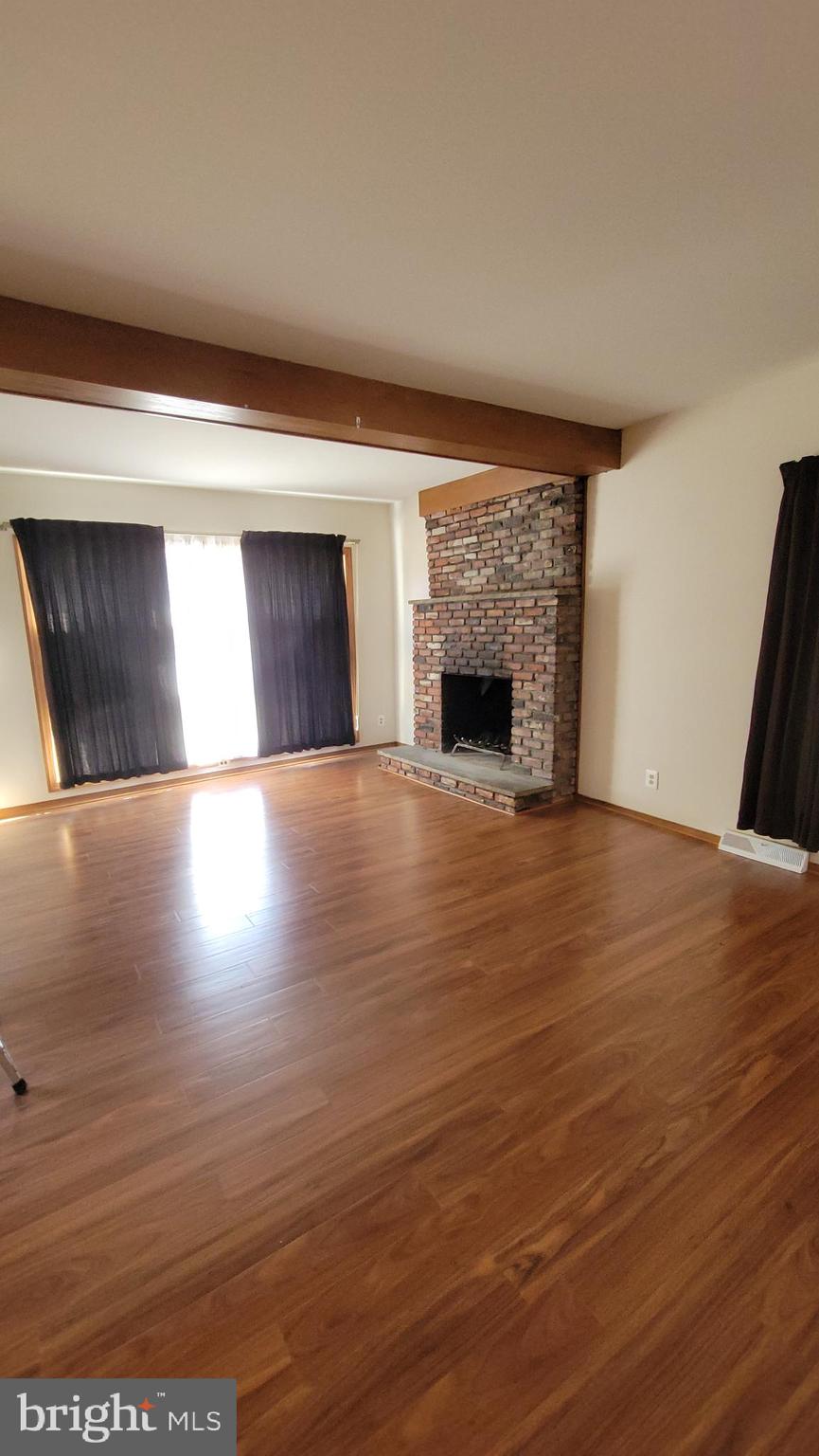569 Lakeside Avenue Woodbury, NJ 08096 - Photo 5 of 9 a view of an empty room with wooden floor and a fireplace