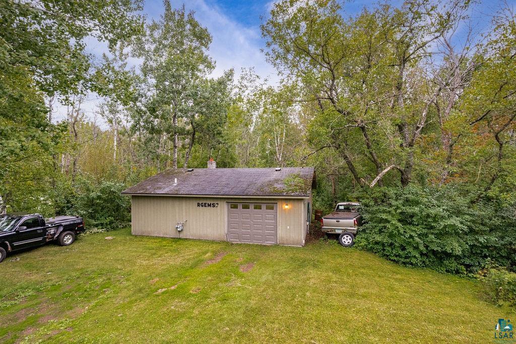 4738 Morris Thomas Road Hermantown, MN 55811 - Photo 6 of 19 Detached outbuilding with a single garage door, green siding, and a sloped roof, surrounded by mature trees and natural landscaping