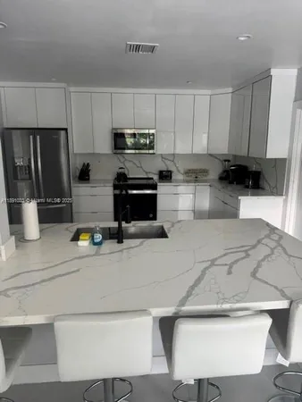 a kitchen with stainless steel appliances kitchen island granite countertop a refrigerator a stove a sink a stove a dining table and chairs