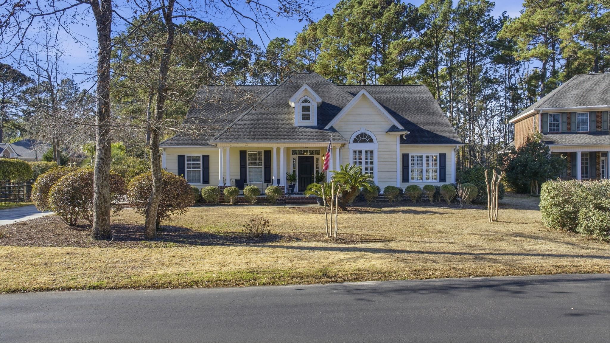 View of front of property featuring covered porch, a front yard, and a shingled roof
