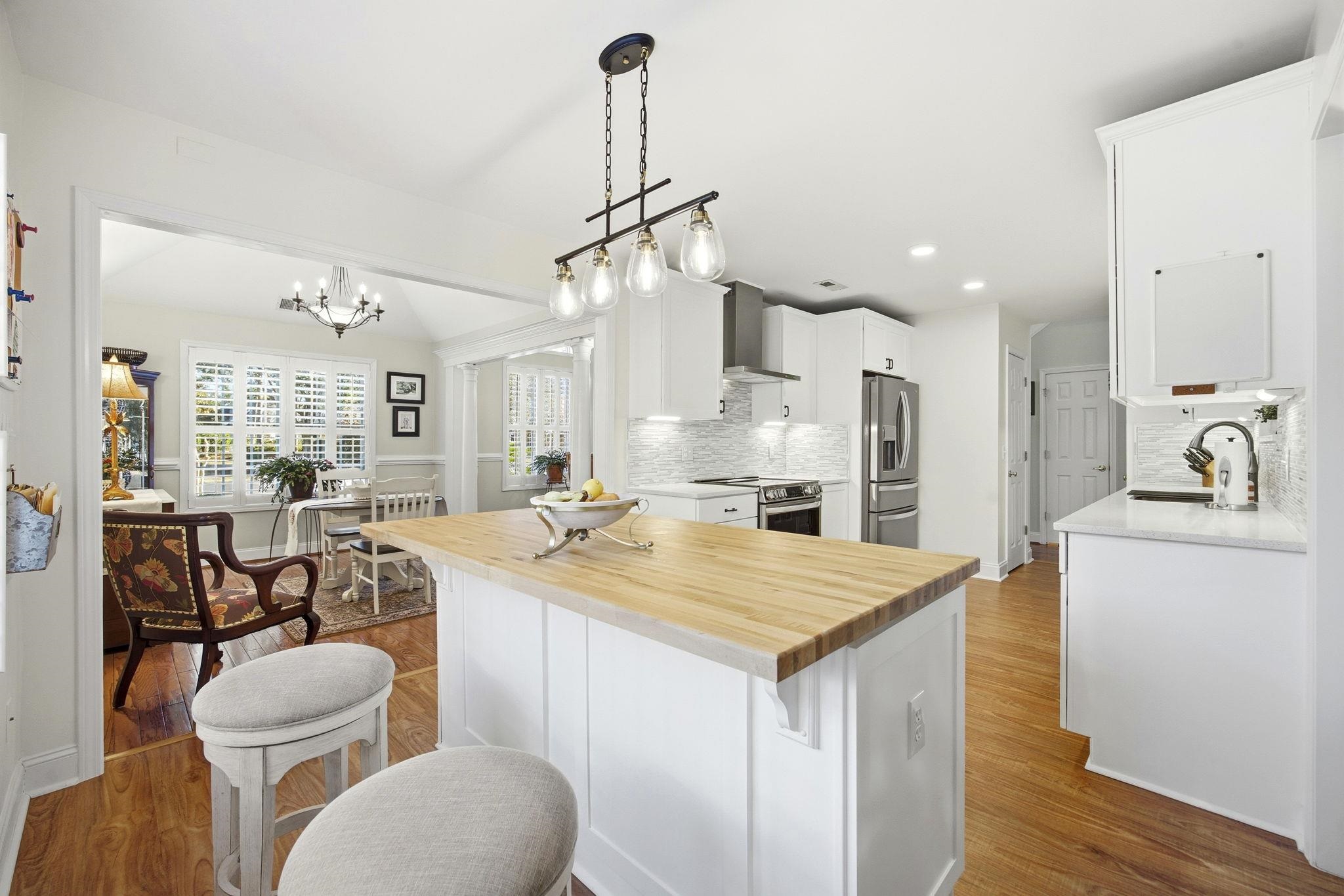 1301 Regent Terrace North Surfside Beach, SC 29575 - Photo 13 of 40 Kitchen with wood counters, white cabinetry, stainless steel appliances, decorative light fixtures, and wall chimney exhaust hood