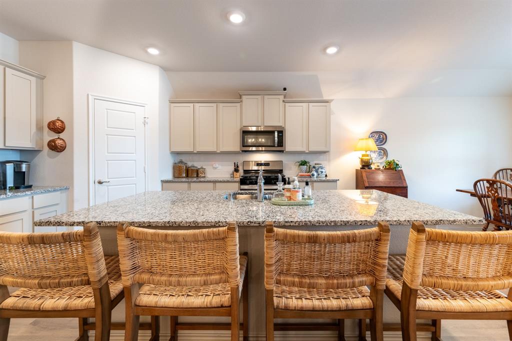 224 Wakefield Road Fate, TX 75189 - Photo 11 of 30 a kitchen with granite countertop a stove white cabinets a dining table and chairs