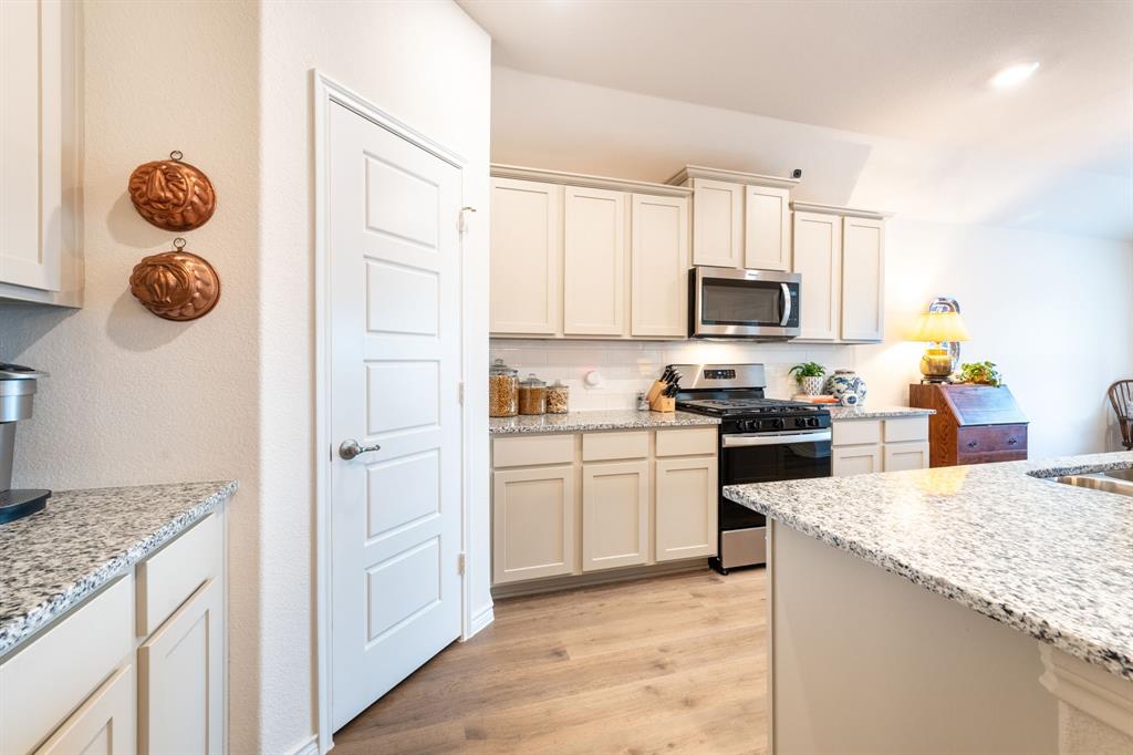 224 Wakefield Road Fate, TX 75189 - Photo 12 of 30 a kitchen with granite countertop a sink a stove top oven and refrigerator