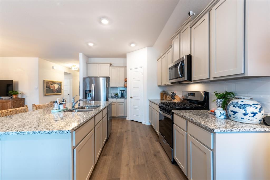 224 Wakefield Road Fate, TX 75189 - Photo 10 of 30 a kitchen with granite countertop kitchen island stainless steel appliances a stove sink and cabinets