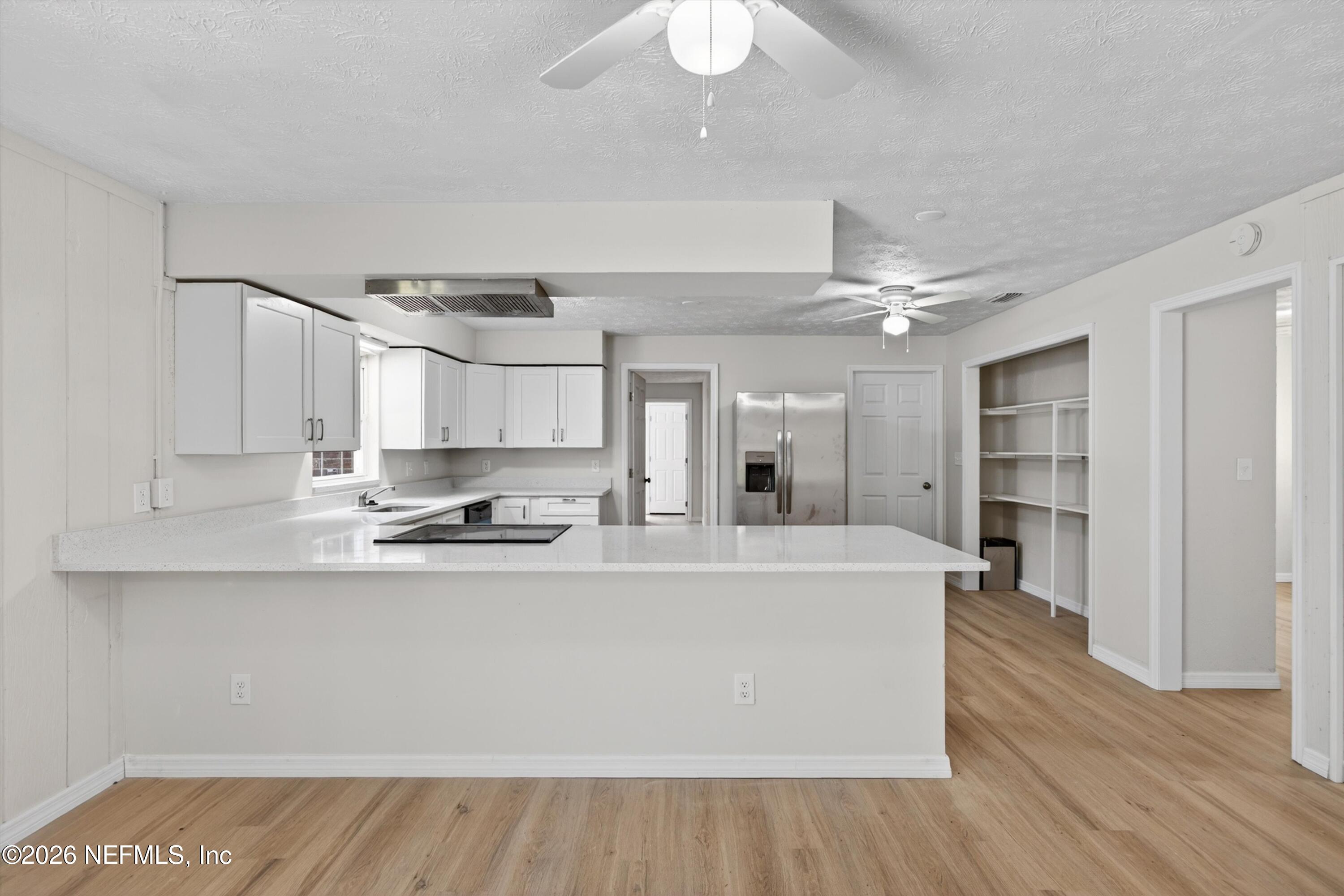 6894 Ridge Street Keystone Heights, FL 32656 - Photo 15 of 40 a large white kitchen with kitchen island a stove a sink dishwasher and a refrigerator with wooden floor