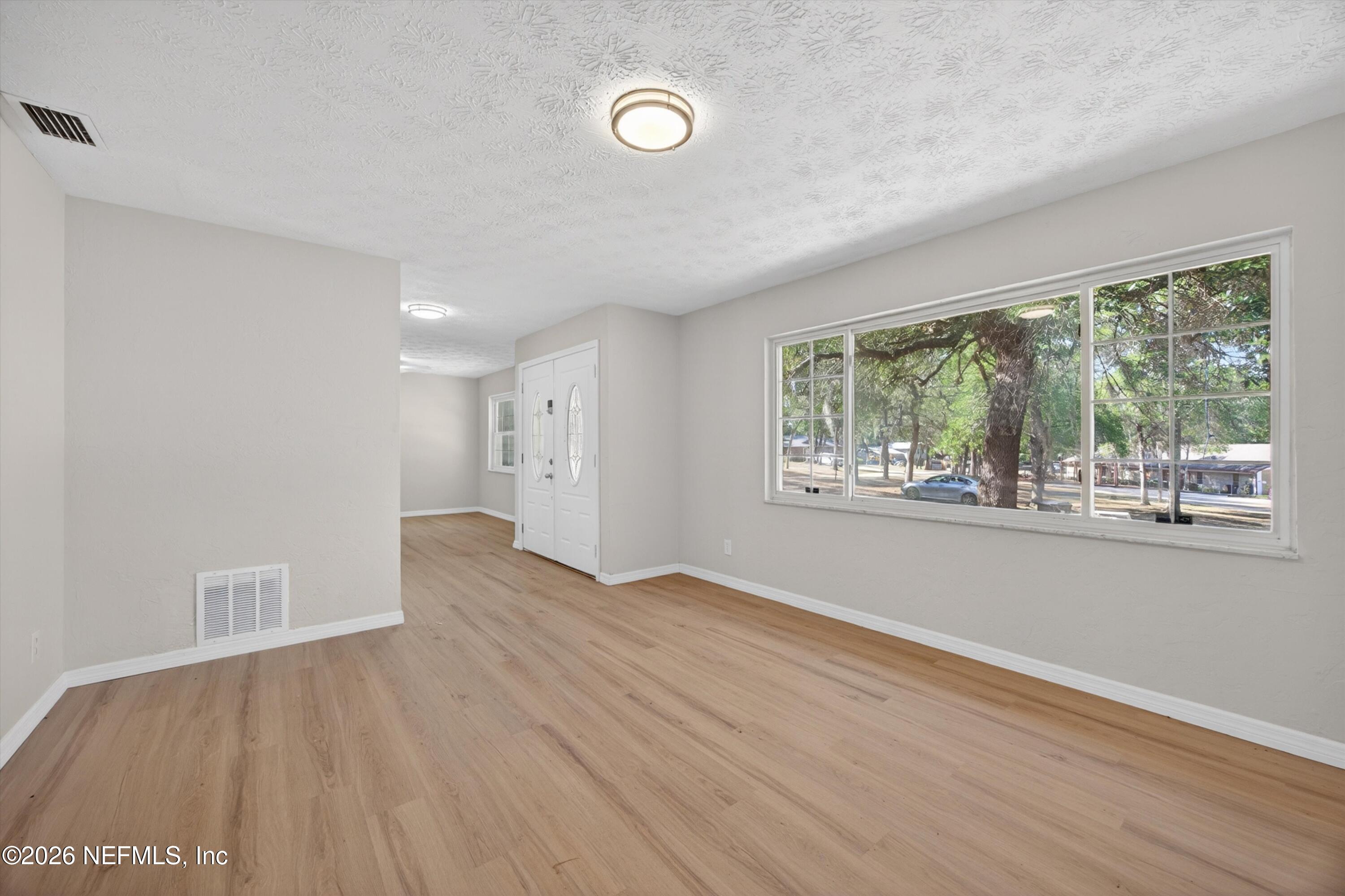 6894 Ridge Street Keystone Heights, FL 32656 - Photo 6 of 40 an empty room with wooden floor and windows