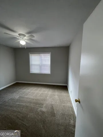 an empty room with a ceiling fan and window