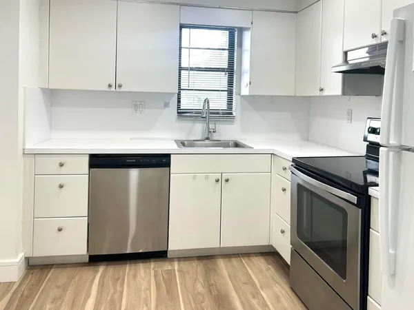 a kitchen with stainless steel appliances granite countertop a sink a stove and a refrigerator with wooden cabinets