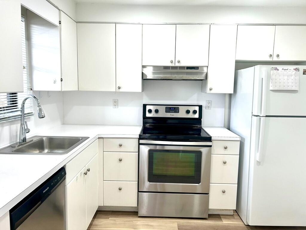 9370 Southwest 8th Street, Unit 202 Boca Raton, FL 33428 - Photo 5 of 46 a kitchen with stainless steel appliances granite countertop a sink a stove and a refrigerator with wooden cabinets
