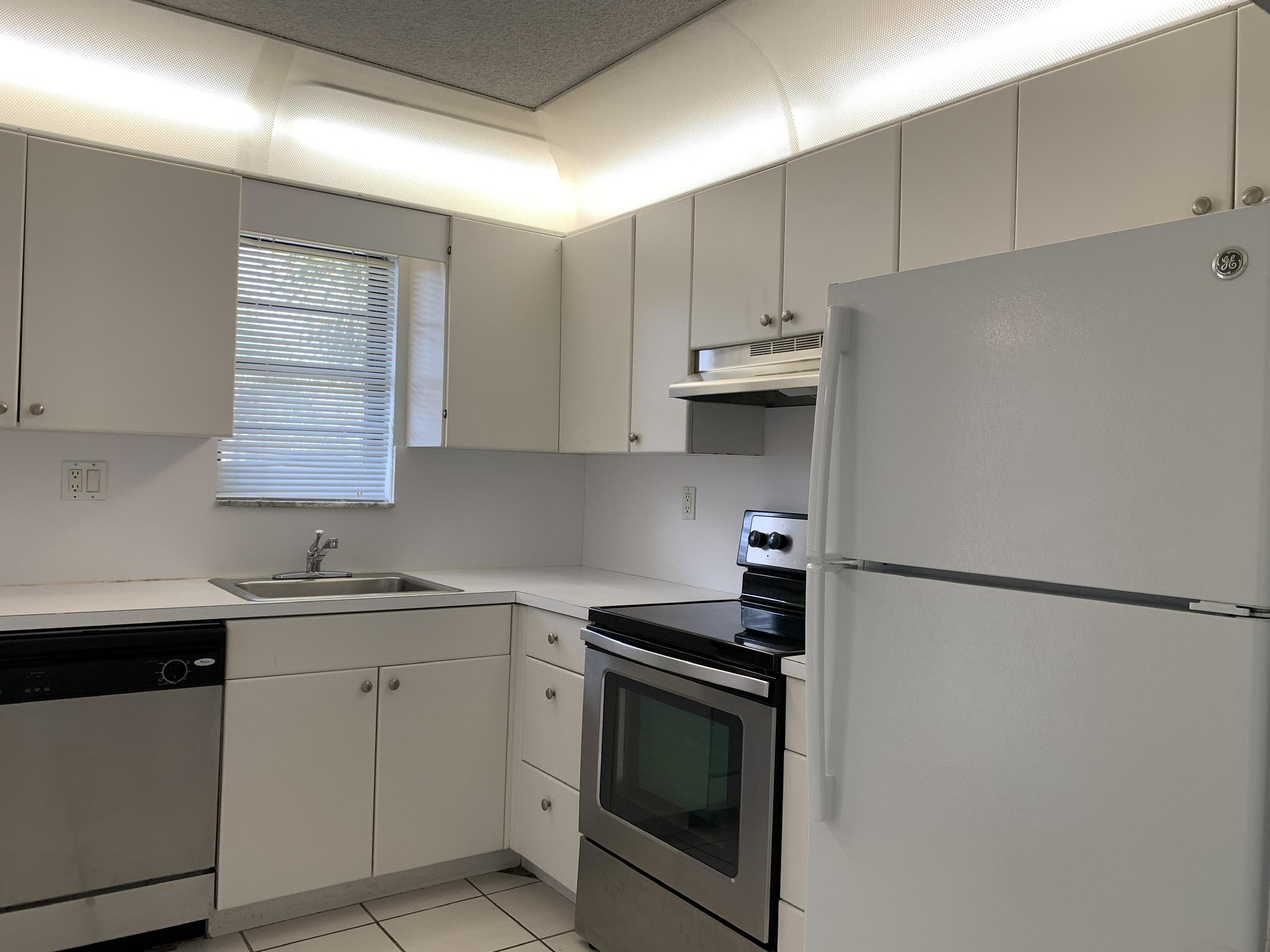 9370 Southwest 8th Street, Unit 202 Boca Raton, FL 33428 - Photo 6 of 46 a kitchen with stainless steel appliances white cabinets and a refrigerator
