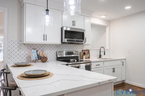 a kitchen with granite countertop a sink a stove and a microwave