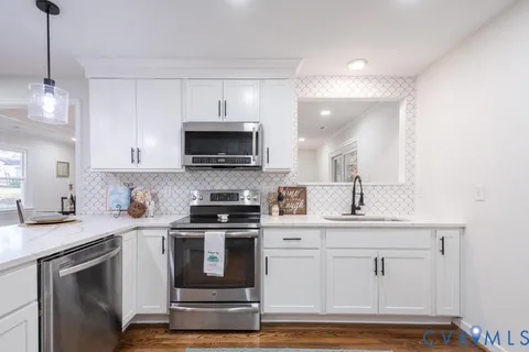 a kitchen with stainless steel appliances granite countertop a sink a stove a microwave and wooden cabinets
