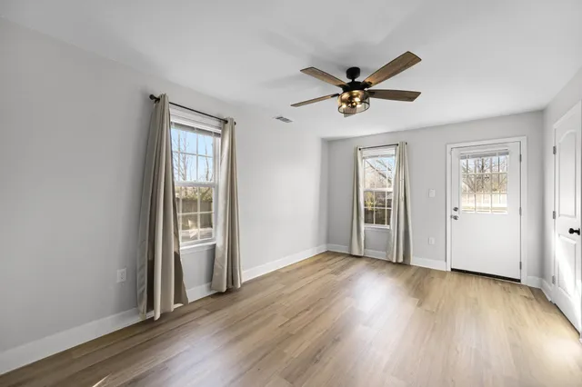 a view of empty room with wooden floor and window