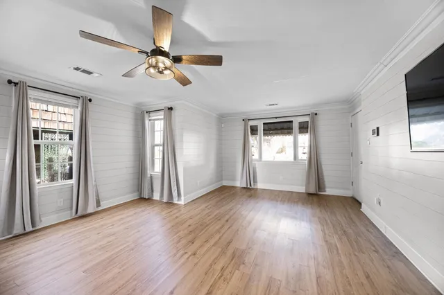 a view of an empty room with wooden floor and a window