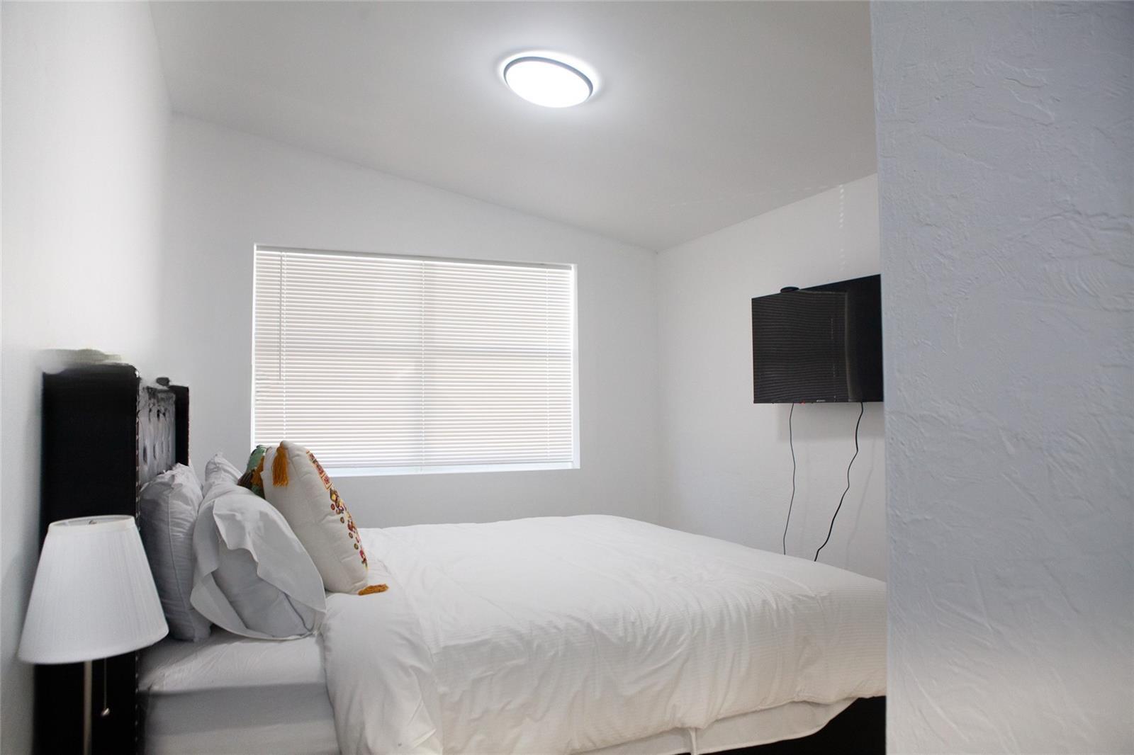 1821 Harding Street, Unit 12 Hollywood, FL 33020 - Photo 10 of 14 a bedroom with a bed and a flat tv screen on a dresser