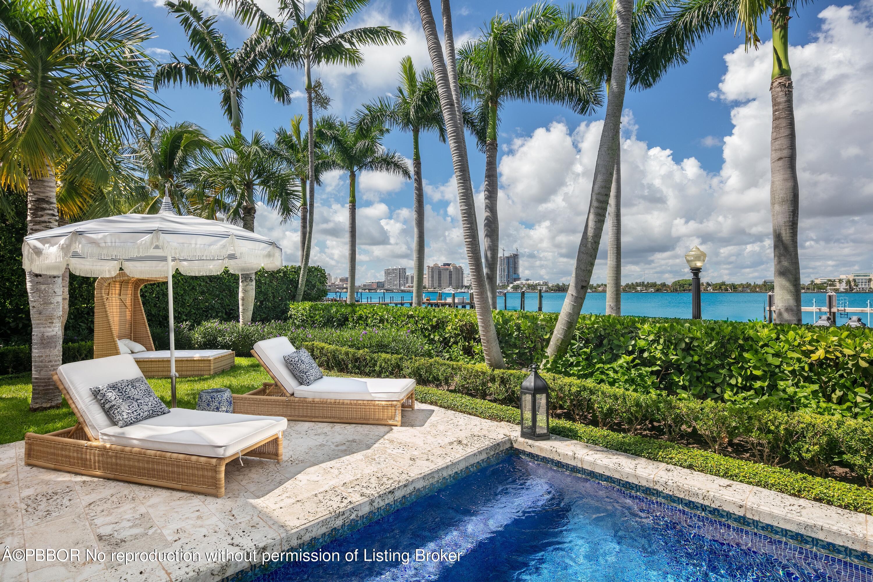 313 Dunbar Road Palm Beach, FL 33480 - Photo 53 of 73 a view of a patio with couches table and chairs under an umbrella with palm trees