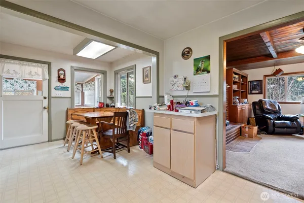 a living room with furniture and a dining table with kitchen appliances