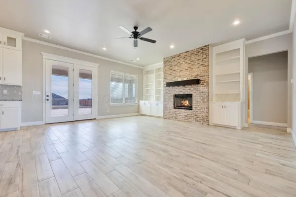 an empty room with wooden floor fireplace and windows