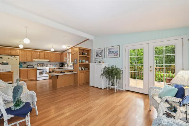 a living room with furniture and a large window with kitchen view