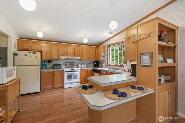 a kitchen with a stove a sink dishwasher a refrigerator and white cabinets with wooden floor