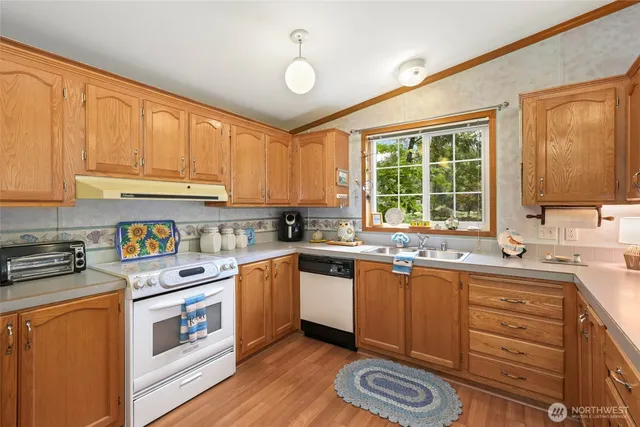 a kitchen with stainless steel appliances granite countertop a sink a stove cabinets and wooden floor