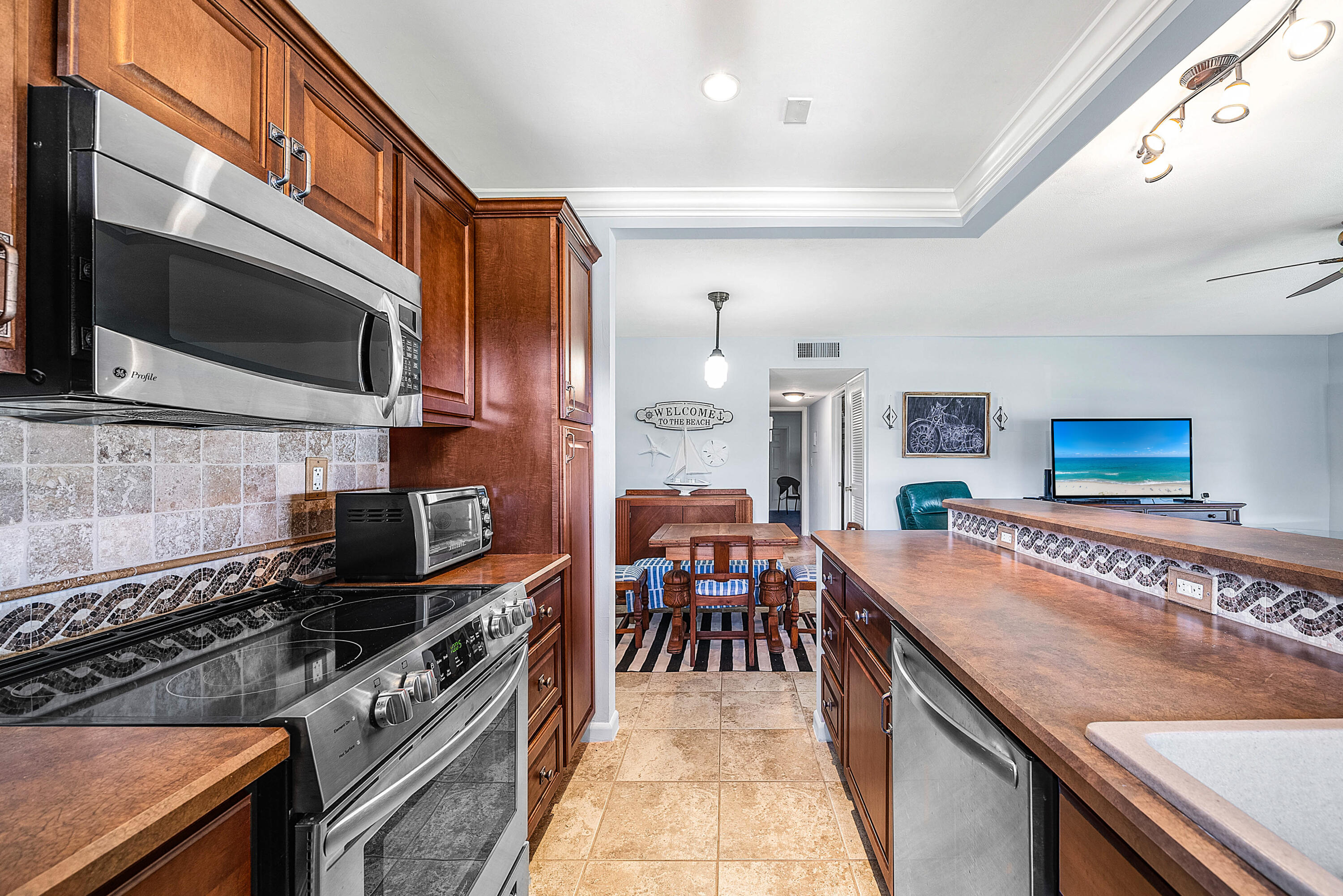 510 High Point Drive, Unit D Delray Beach, FL 33445 - Photo 8 of 23 a kitchen with stainless steel appliances granite countertop a stove top oven a sink dishwasher a dining table and chairs with wooden floor